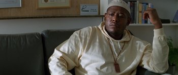 Movie still from “Species” (1995), directed by Roger Donaldson – A man sitting on top of a couch in a room; Close Up shot, Low angle