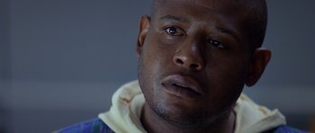 Movie still from “Species” (1995), directed by Roger Donaldson – A man's face in a dark room; Close Up shot, Low angle