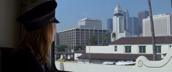 Movie still from “Species” (1995), directed by Roger Donaldson – A woman in a police uniform looking out of a car window; Wide shot, Over the shoulder angle