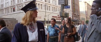 Movie still from “Species” (1995), directed by Roger Donaldson – A woman in a police officer's uniform on a city street; Medium shot, Low angle