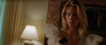 Movie still from “Species” (1995), directed by Roger Donaldson – A beautiful woman holding a remote in her hand; Close Up shot, Low angle