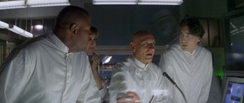 Movie still from “Species” (1995), directed by Roger Donaldson – A group of men in white lab coats in a lab; Medium shot, Low angle