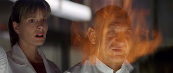 Movie still from “Species” (1995), directed by Roger Donaldson – A man with a bald head is looking out a window; Close Up shot, Low angle