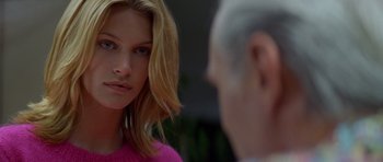 Movie still from “Species” (1995), directed by Roger Donaldson – A young woman in a pink sweater looks at an older man in a pink sweater; Close Up shot, Over the shoulder angle