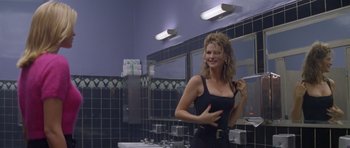 Movie still from “Species” (1995), directed by Roger Donaldson – A woman in a black dress in a bathroom; Medium shot, Over the shoulder angle