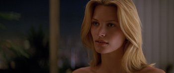 Movie still from “Species” (1995), directed by Roger Donaldson – A woman with blonde hair is looking at the camera; Close Up shot, Over the shoulder angle