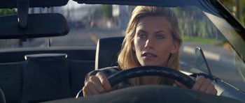 Movie still from “Species” (1995), directed by Roger Donaldson – A woman sitting in the drivers seat of a car; Close Up shot, Over the shoulder angle