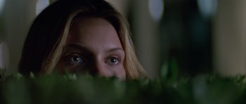 Movie still from “Species” (1995), directed by Roger Donaldson – A person's face with plants in the background; Close Up shot, Low angle