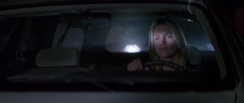 Movie still from “Species” (1995), directed by Roger Donaldson – A woman driving a car at night in the dark; Close Up shot, Over the shoulder angle