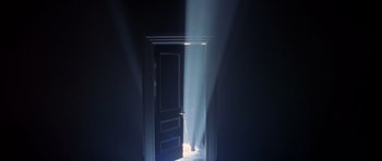 Movie still from “Species” (1995), directed by Roger Donaldson – A door that is opened to a room with light coming through it; Wide shot, High angle