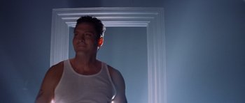 Movie still from “Species” (1995), directed by Roger Donaldson – A man standing in front of a mirror in a room; Medium shot, Low angle