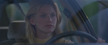 Movie still from “Species” (1995), directed by Roger Donaldson – A woman sitting in the driver's seat of a car; Close Up shot, Over the shoulder angle