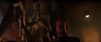 Movie still from “Species” (1995), directed by Roger Donaldson – A man standing in front of a statue in a dark room; Medium shot, Low angle