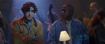 Movie still from “Species” (1995), directed by Roger Donaldson – Two men standing next to each other in front of a lamp; Medium shot, Low angle