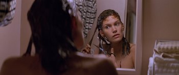 Movie still from “Species” (1995), directed by Roger Donaldson – A woman combing her hair in front of a bathroom mirror; Close Up shot, Low angle