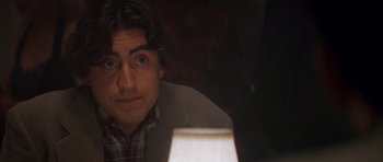 Movie still from “Species” (1995), directed by Roger Donaldson – A person sitting at a table; Close Up shot, Over the shoulder angle