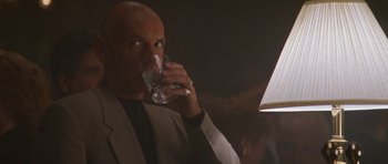 Movie still from “Species” (1995), directed by Roger Donaldson – A man in a suit drinking a glass of water; Close Up shot, Over the shoulder angle
