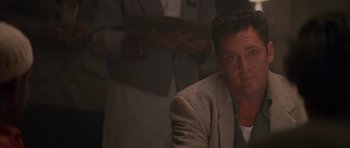 Movie still from “Species” (1995), directed by Roger Donaldson – A person wearing a suit and tie; Close Up shot, Low angle