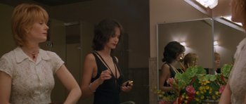 Movie still from “Species” (1995), directed by Roger Donaldson – A woman in a black dress holding a cell phone; Medium shot, Over the shoulder angle