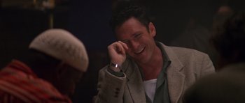Movie still from “Species” (1995), directed by Roger Donaldson – A man in a jacket smiling at someone; Close Up shot, Over the shoulder angle