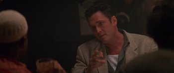 Movie still from “Species” (1995), directed by Roger Donaldson – A person sitting at a table; Close Up shot, Over the shoulder angle