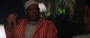 Movie still from “Species” (1995), directed by Roger Donaldson – A man wearing a striped jacket and a white hat; Close Up shot, Low angle