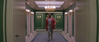Movie still from “Species” (1995), directed by Roger Donaldson – A man walking down a hall way wearing a red jacket; Wide shot, Low angle