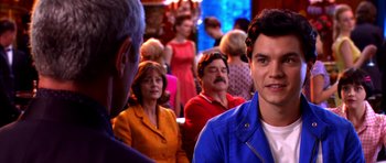 Movie still from “Speed Racer” (2008), directed by Lilly Wachowski – A group of people sitting in a room; Close Up shot, Over the shoulder angle