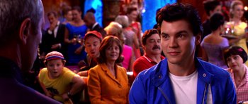 Movie still from “Speed Racer” (2008), directed by Lilly Wachowski – A man standing in front of a group of people; Close Up shot, Over the shoulder angle