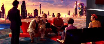 Movie still from “Speed Racer” (2008), directed by Lilly Wachowski – A group of people sitting on a couch in front of a city; Wide shot, Over the shoulder angle