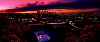 Movie still from “Speed Racer” (2008), directed by Lilly Wachowski – A view of a city at night with a car in the foreground; Extreme Wide shot, High angle