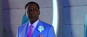 Movie still from “Speed Racer” (2008), directed by Lilly Wachowski – A man in a blue suit with a rose in his lapel; Close Up shot, Over the shoulder angle