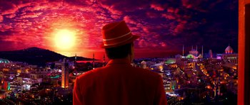 Movie still from “Speed Racer” (2008), directed by Lilly Wachowski – A man wearing a red hat looking out over a city at sunset; Medium shot, Low angle