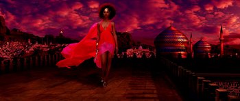 Movie still from “Speed Racer” (2008), directed by Lilly Wachowski – A woman in a red and pink dress walking down a street; Wide shot, Low angle