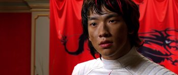 Movie still from “Speed Racer” (2008), directed by Lilly Wachowski – A young man in a white shirt is looking at the camera; Close Up shot, Low angle