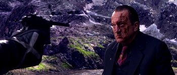 Movie still from “Speed Racer” (2008), directed by Lilly Wachowski – A man in a suit and a red neck tie in front of a mountain; Close Up shot, Over the shoulder angle