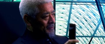 Movie still from “Speed Racer” (2008), directed by Lilly Wachowski – An older man with grey hair looking at a cell phone; Extreme Close Up shot, Low angle