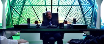 Movie still from “Speed Racer” (2008), directed by Lilly Wachowski – An older man sitting at a desk in front of a window; Medium shot, Over the shoulder angle