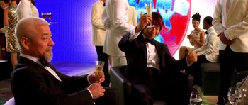 Movie still from “Speed Racer” (2008), directed by Lilly Wachowski – A man in a suit and tie holding up a pair of scissors; Medium shot, Low angle