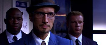 Movie still from “Speed Racer” (2008), directed by Lilly Wachowski – A man in a blue suit and a man in a blue suit and a hat; Close Up shot, Over the shoulder angle