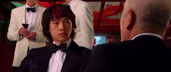 Movie still from “Speed Racer” (2008), directed by Lilly Wachowski – A man in a suit and bow tie; Close Up shot, Over the shoulder angle