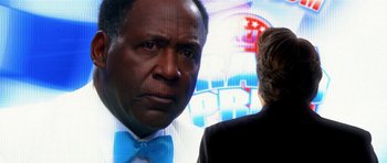 Movie still from “Speed Racer” (2008), directed by Lilly Wachowski – A man in a blue bow tie and a woman in a black suit; Close Up shot, Over the shoulder angle