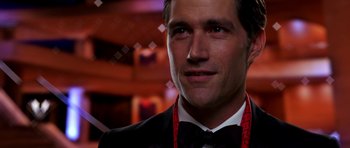 Movie still from “Speed Racer” (2008), directed by Lilly Wachowski – A person wearing a suit and a bow tie; Close Up shot, Over the shoulder angle