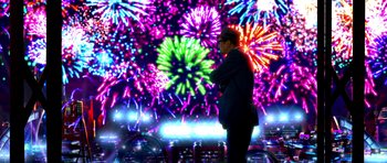 Movie still from “Speed Racer” (2008), directed by Lilly Wachowski – A man standing in front of a colorful fireworks display; Extreme Wide shot, Over the shoulder angle