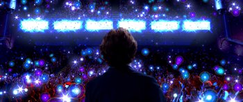 Movie still from “Speed Racer” (2008), directed by Lilly Wachowski – A man standing in front of an audience at an event; Extreme Wide shot, Low angle