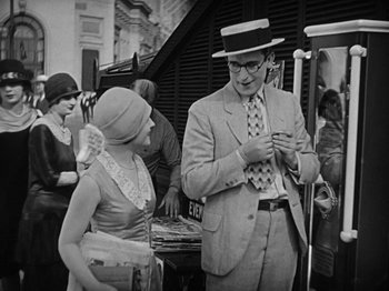 Movie still from “Speedy” (1928), directed by Ted Wilde – An old photo of a man and a woman looking at a cell phone; Medium shot, Over the shoulder angle