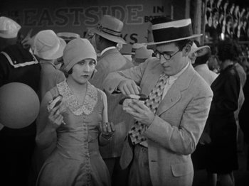 Movie still from “Speedy” (1928), directed by Ted Wilde – A man and a woman are standing in a crowd of people; Medium shot, High angle