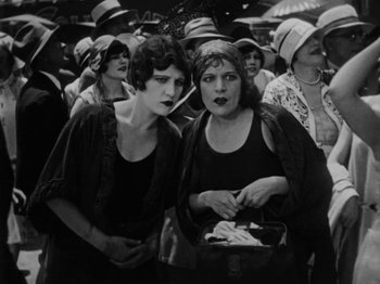 Movie still from “Speedy” (1928), directed by Ted Wilde – A couple of women standing next to each other in a crowd; Medium shot, High angle