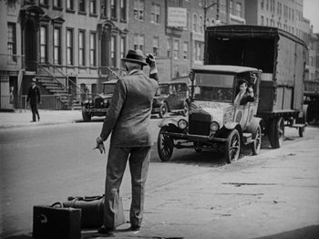 Movie still from “Speedy” (1928), directed by Ted Wilde – An old photo of a man directing traffic in a city; Wide shot, Over the shoulder angle