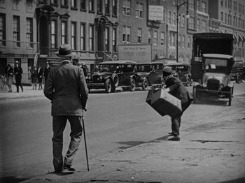 Movie still from “Speedy” (1928), directed by Ted Wilde – An old photo of two men on the sidewalk; Wide shot, Low angle